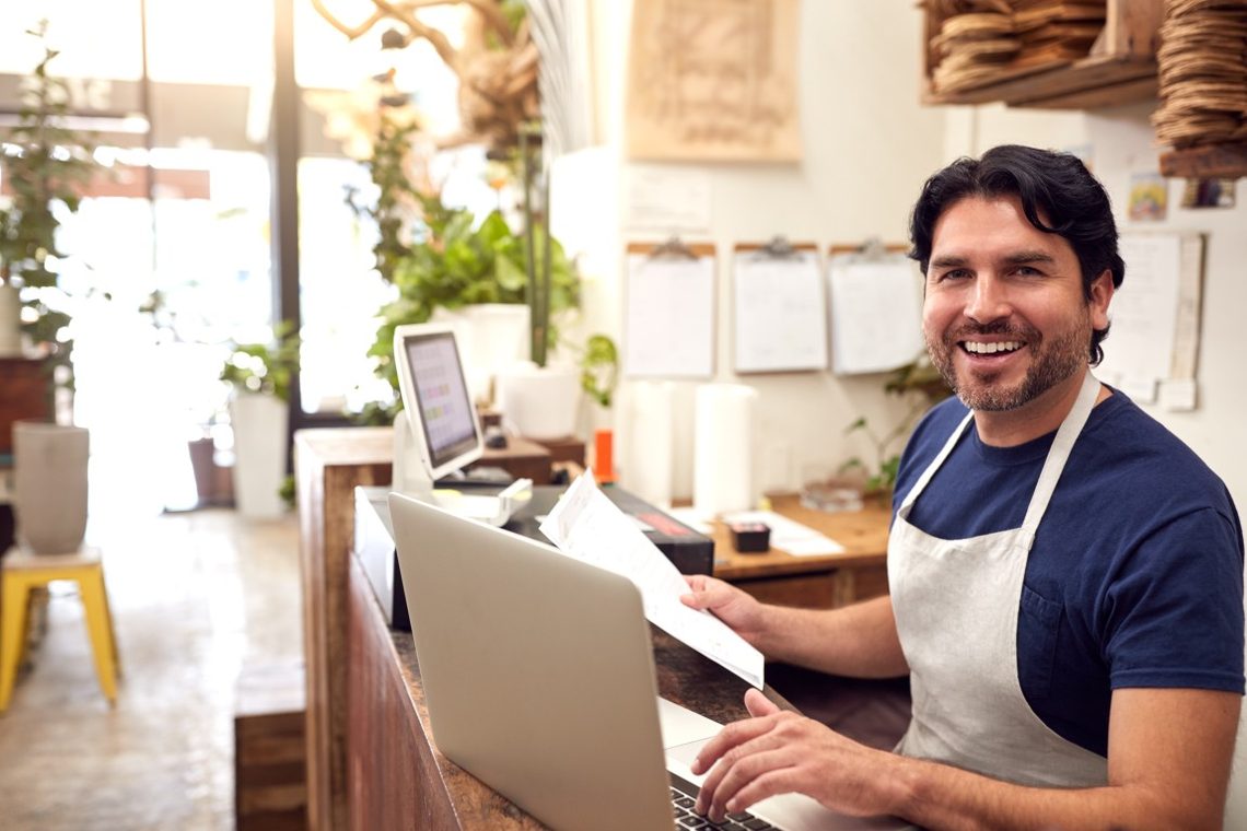 Smiling business owner working at a shop counter